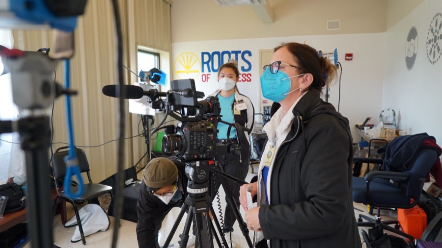 The crew set up cameras and lights around an interview subject on location.